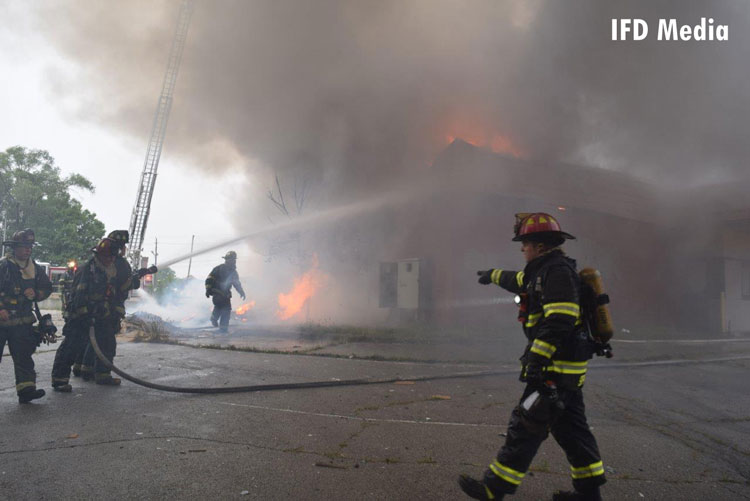 Indianapolis firefighters use hoselines to pour water on a fire in a vacant building