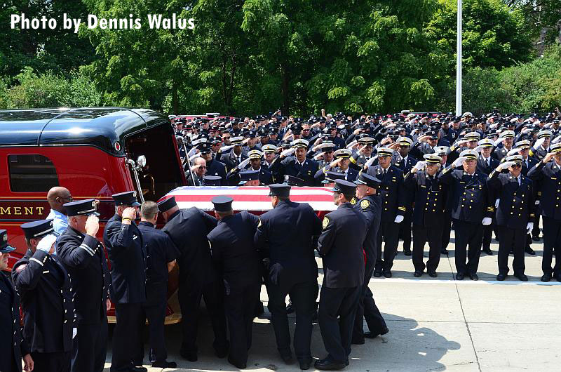 Firefighters load the coffin carrying the body of Detroit Firefighter Kevin Ramsey onto an apparatus