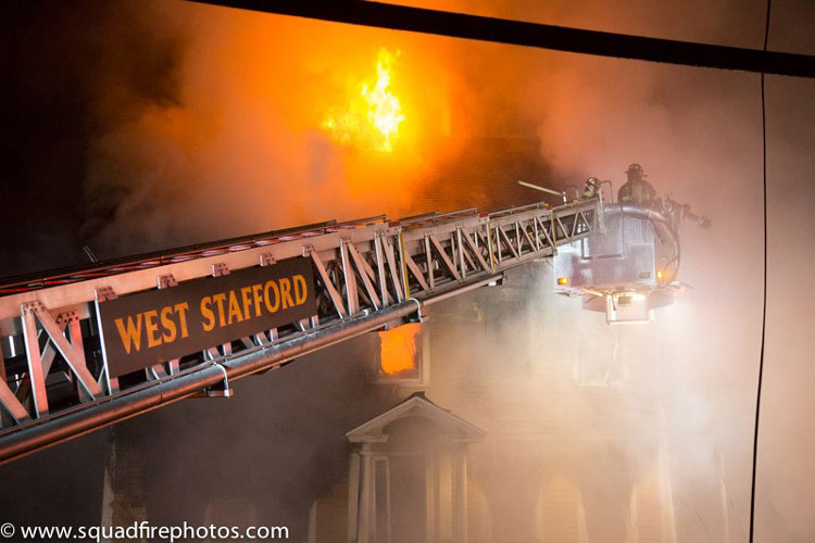 Firefighters in a tower ladder bucket fighting fire in a house