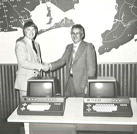 (2) John Mohan, director of the New York Fire Department bureau of information and computer services, left, congratulates Ron Scherma, vice president of Brad Nation, on completion of computerized dispatch system. Maps of five boroughs are in background.