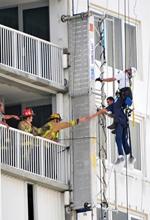 (10) Fort Lauderdale firefighters must make this rescue being mindful of the weight of the scaffold. One anchor point has already failed. The failure of the second anchor could shear their ropes if the other anchor fails. <i>[Photo courtesy of the Fort Lauderdale (FL) Fire Department.]</i>