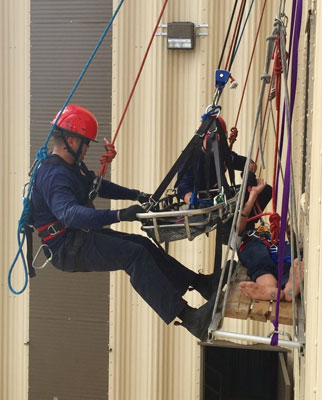 (12) Coral Springs (FL) Regional Institute of Public Safety students practice moving a worker with a spinal injury into a Stokes basket. 