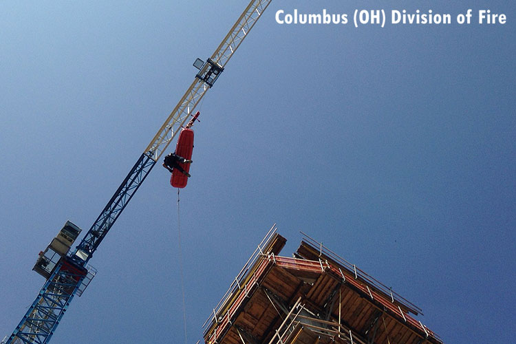 Firefighter with patient in a stokes descending from a high point on a construction site