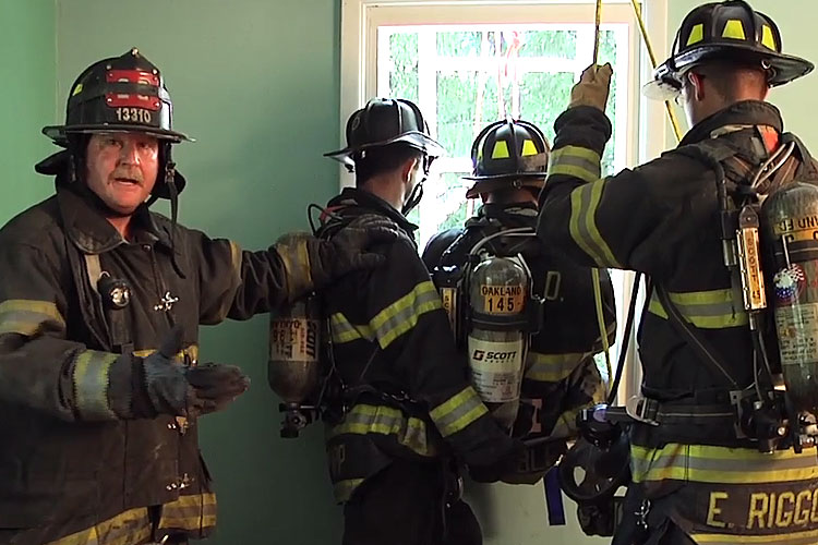 Firefighters prepare to remove an injured member through a window