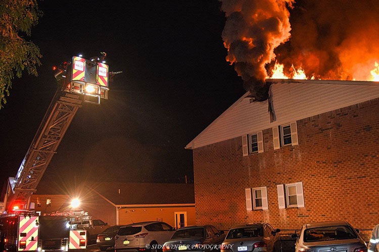 Tower ladder being raised to fight fire on the roof of an apartment complex