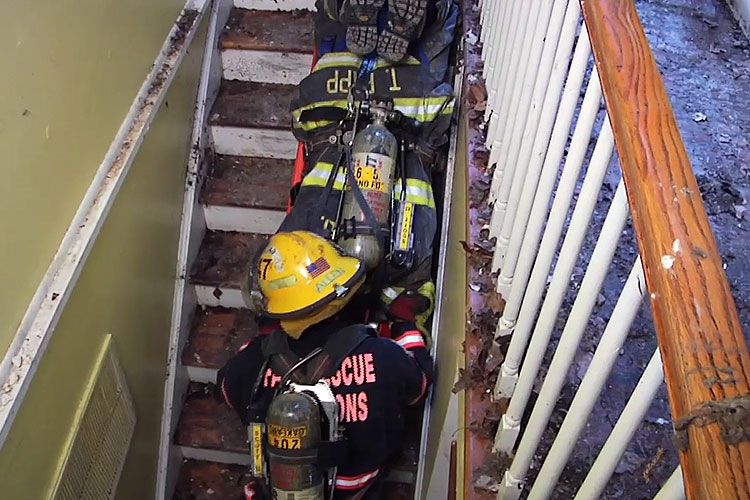 Firefighter bringing a down member down the stairs on a rescue board