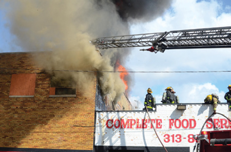 (5) After the transition to defensive operations, firefighters on an exposure building roof prepare to operate from a point of advantage.