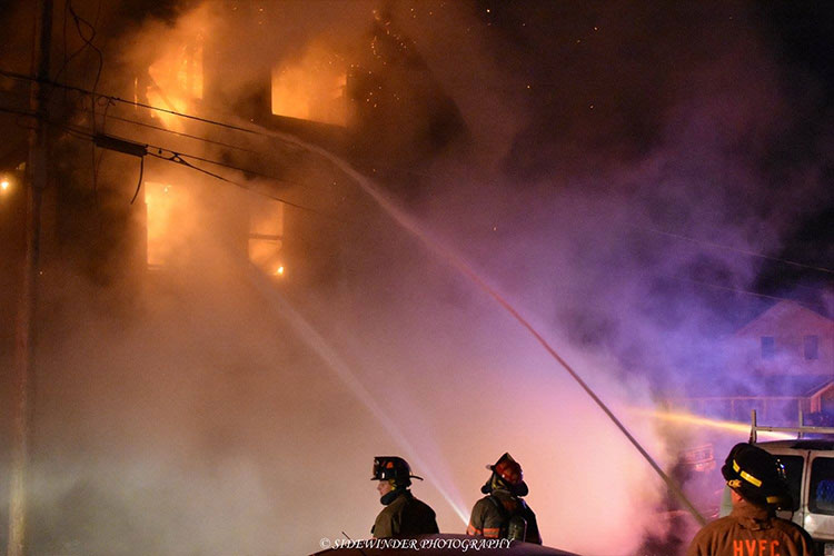 Firefighters train hosestreams through the windows of a burning residence