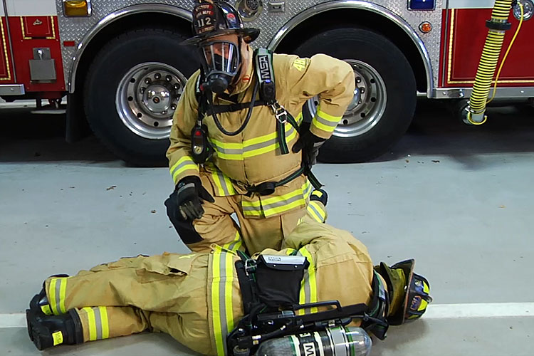 Firefighter peforms buddy breathing technique on a down colleague