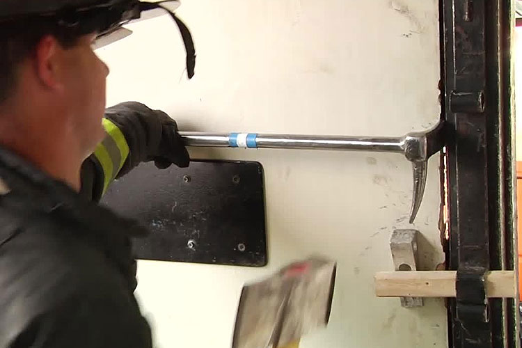 Firefighter using a halligan to force entry on a door