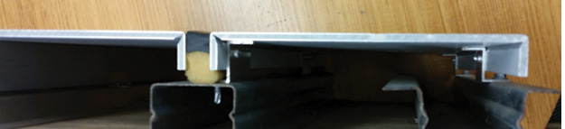 5) A cross-section of panels installed using the Cassette method. Note how the panel’s edges are bent 90° like an inverted “U” and that each panel is positively secured by a bracket and screw. This is a much more secure method than the Direct Stick. However, the system is still prone to unchecked fire travel in the void space at the rear of the panels. Fire stopping is essential when using either method. (Photo by author.)