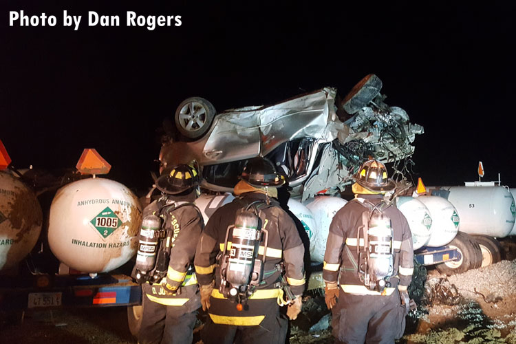 Firefighters at the scene of a car that has rolled over onto anhydrous ammonia tanks