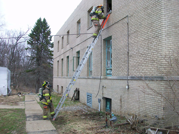 Firefighters ascend a ladder