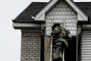 Firefighter on ladder near roofline