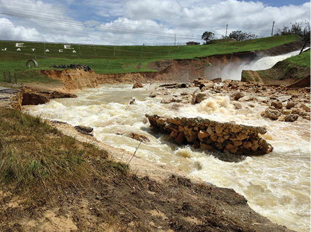 (3) The Guajataca Dam, viewed from the backside. The spillway is damaged, and major erosion is occurring downstream. The dam, itself, is intact.