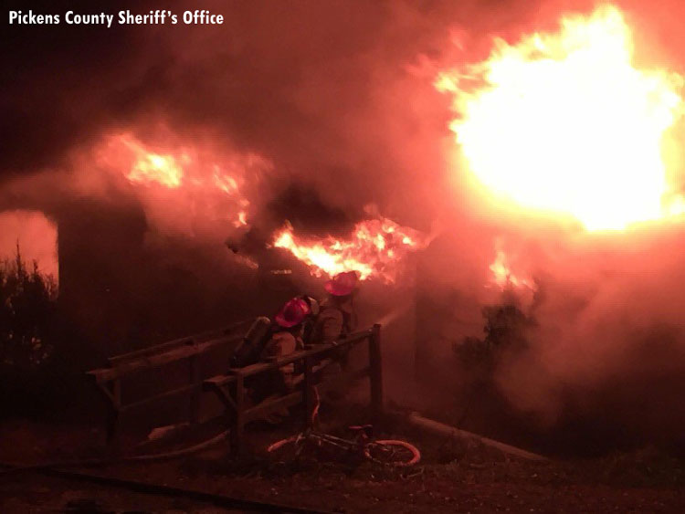 Firefighters advance a hoseline into a burning building