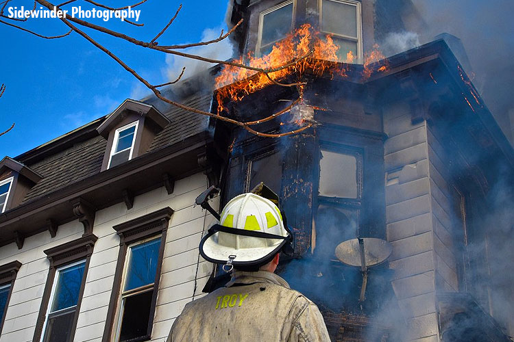 A firefighter stare up at fire from a house fire