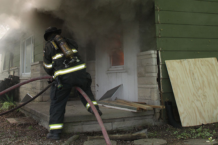 Firefighter manages a hoseline outside a residential fire