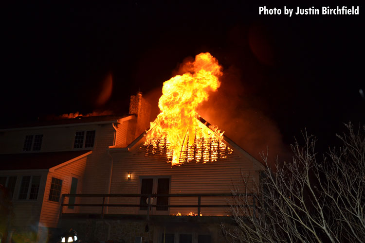 Flames vent from the top of a large home