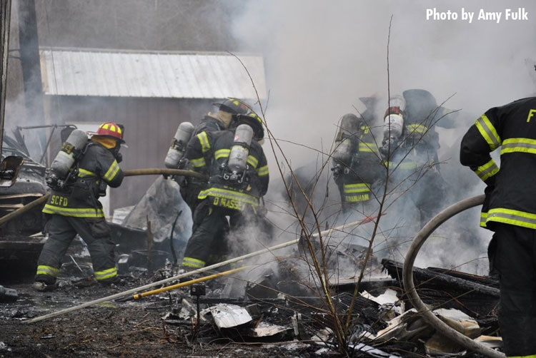 Firefighters perform overhaul after trailer fire