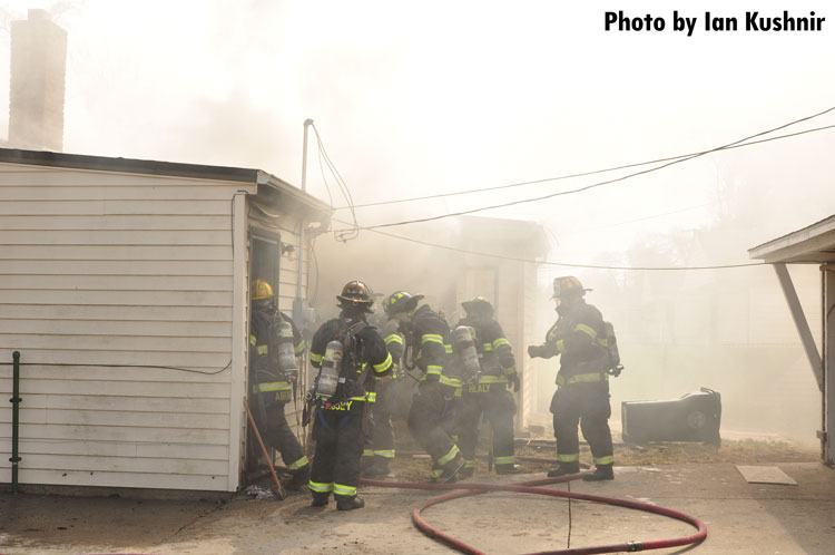 Firefighters make entry at the scene of a house fire