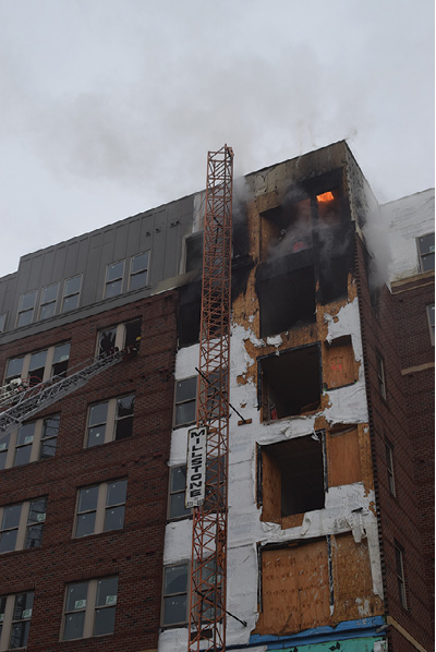 (3) Fire was visible in the attic space above the seventh floor after the fire in the sixth-floor apartment was knocked down. Fire extension was rapid in the concealed fire-rated roof/ceiling assembly. (Photo by Mark Brady.)