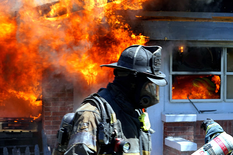 Firefighter in front of a burning home during FDIC training