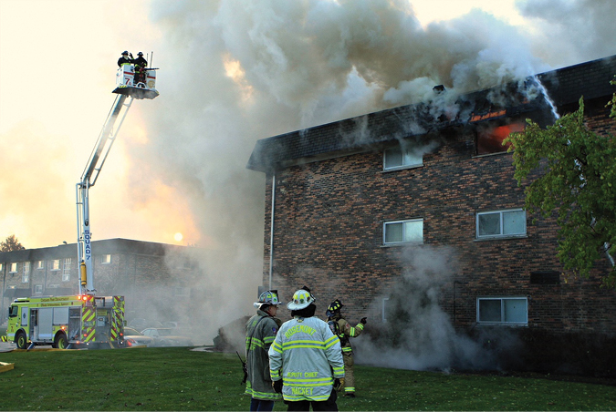 (1) Heavy fire can be seen in the top-floor unit of this three-story building. Because of the amount of fire burning in the unit and into the cockloft, defensive operations are being set up. (Photos by Tim Olk.)  