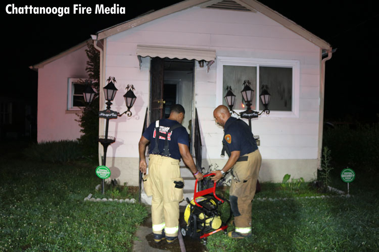 Firefighters move a fan at a house fire