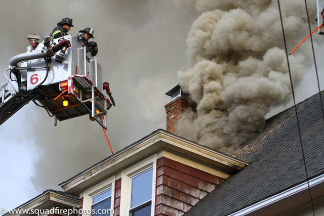 Firefighters in a bucket as smoke vents through roof