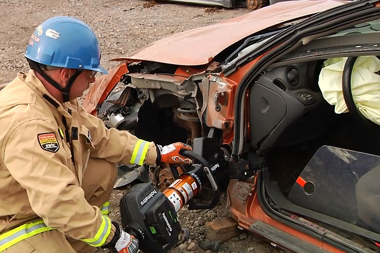 Firefighter uses hydralic tools to make cut on vehicle