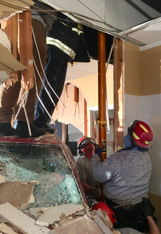 Firefighters install a pneumatic shore next to the pickup truck