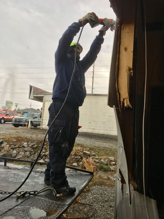 Firefighters cut the metal exterior wall to create access for the tow truck bed