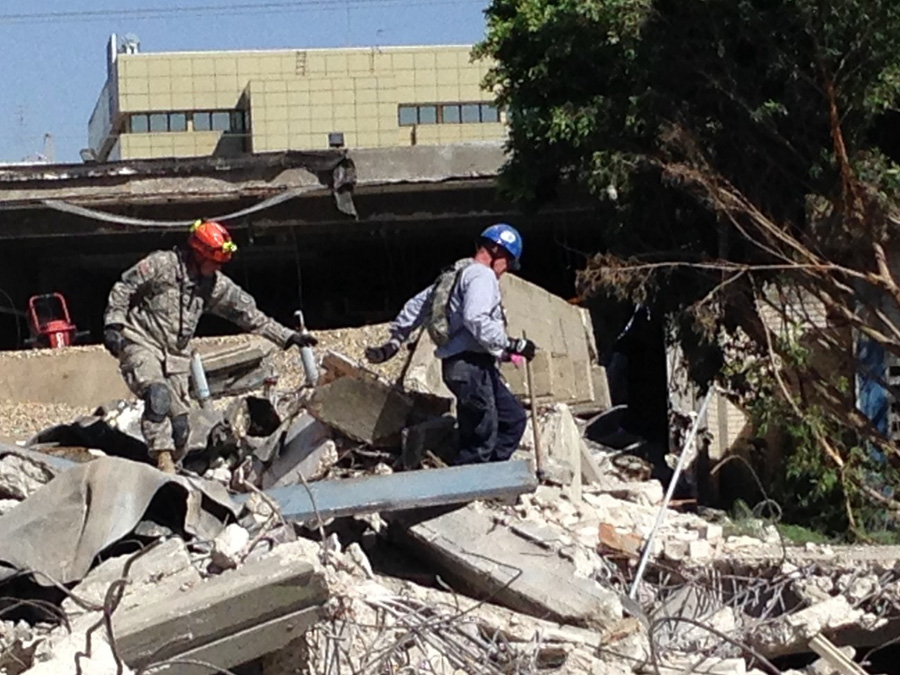 Members of the Indiana National Guard and Indiana Task Force 1 search a collapse area for potential void spaces, applying shared “peel and tunnel” search and extraction techniques. 