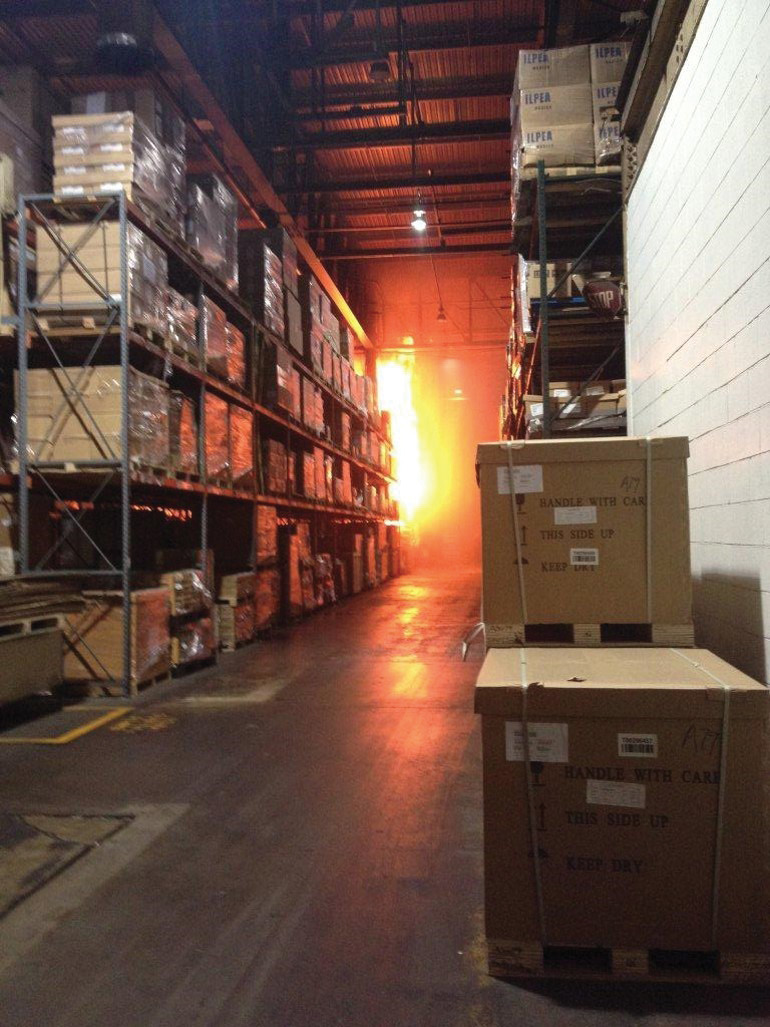 This photo, taken by an evacuating employee, shows the fire in an incipient stage at the end of a row of racks. [Photo courtesy of the Louisville (KY) Metro Arson Squad.]