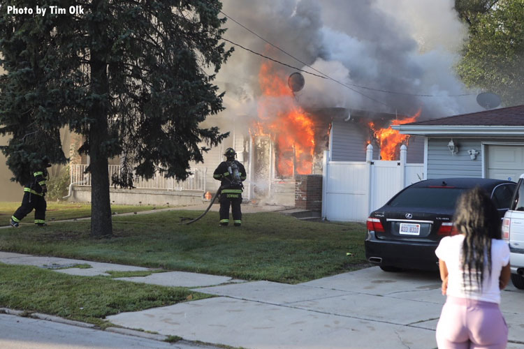 Firefighters stretch hoseline at house fire