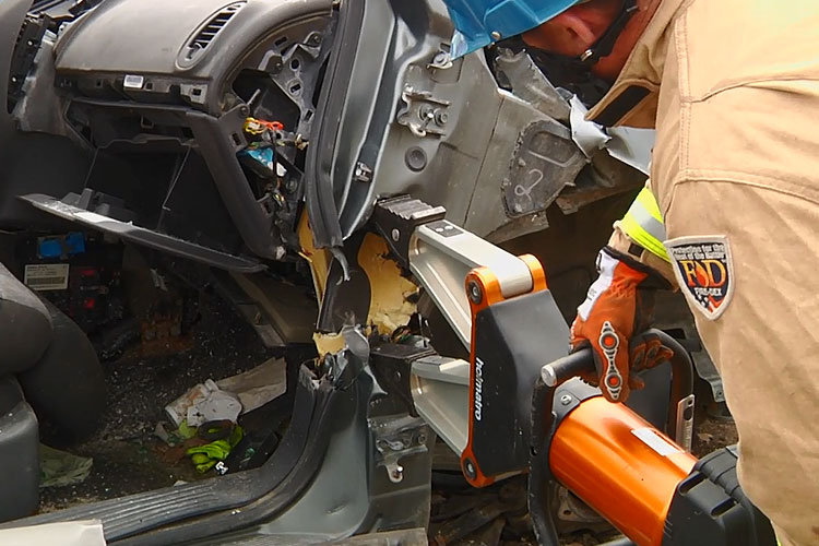 Firefighter using Holmatro spreader for dash push