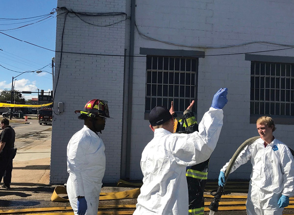 Members of the Regional Hazardous Materials Response Team decontaminate a firefighter on site. 