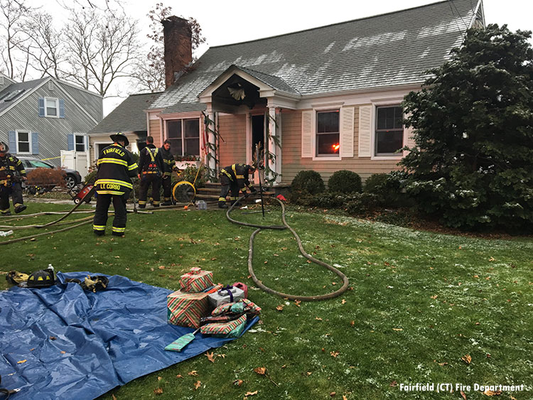 Firefighters bring Christmas presents out of the fire building and put them on the lawn