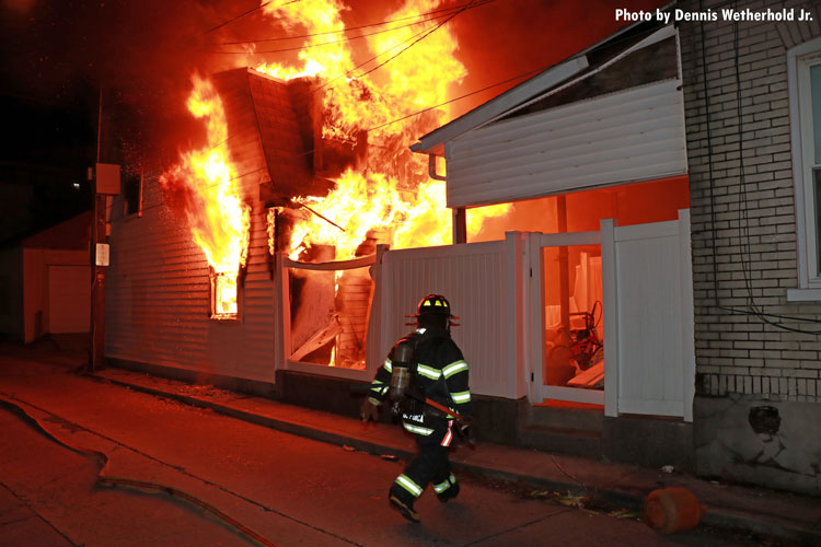 Firefighter strides toward a burning building