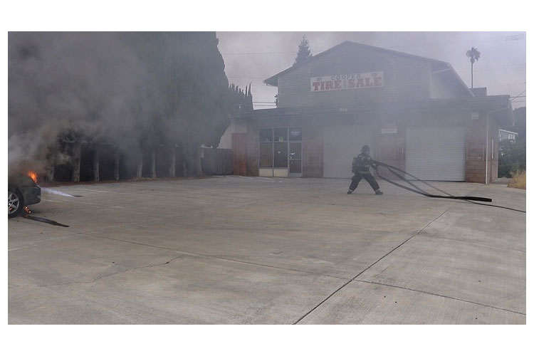 Firefighter pulls a line at a vehicle fire