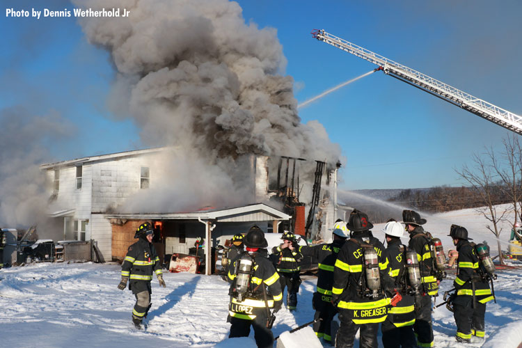 Firefighters and aerial ladder at burning home