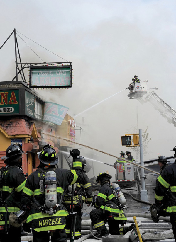 Placing the tower ladder’s bucket onto the sidewalk at taxpayers and strip malls is a great method of applying water into the structure. Always size up the conditions of the parapet before, during, and after operating there. (Photo by Lou Minutoli.)