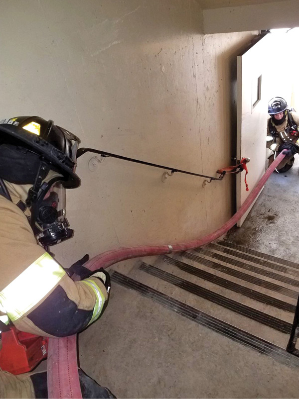 Personnel have to be strategically positioned on a hoseline to keep it moving. A firefighter pulls hose from the floor below the fire into the attack stairwell and feeds it up to a firefighter positioned at the half-landing between the fire floor and floor below.