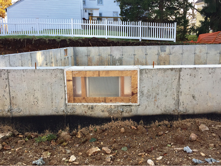 The basement window sits flush and tight in the rough opening of the foundation. Notice the sill plate has yet to be placed. 