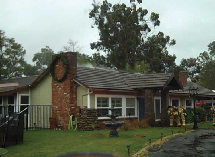 Note the light smoke from the ridge of the roofline. Many fires start by looking rather innocuous on arrival. Get ahead of the incident early. The fire was deep seated in the attic space, and the smoke was affected by high winds. (Photos by Anthony Kastros.)