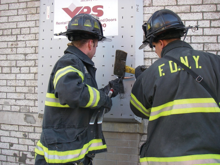 (17) Firefighters use forcible entry tools to shear the bolt head on a VPS window guard.