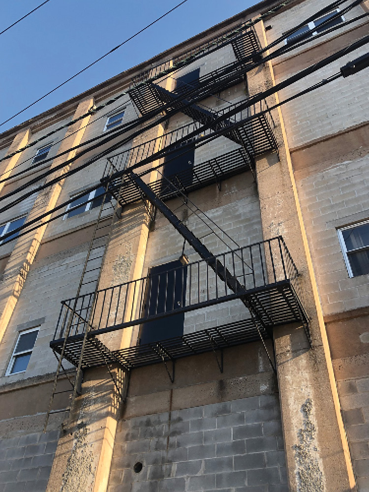 This building contains two second-story drop ladders. The one on the left is right above an awning, which will inhibit its use. The one on the right provides egress from a door on the second floor that passes over the roof.