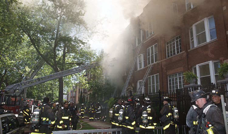 (2) On the front of the building, members placed portable ladders to the fire building and are now placing portable ladders to the top floor of the exposures on both sides. This will be a means for the members inside to evacuate in an emergency. 