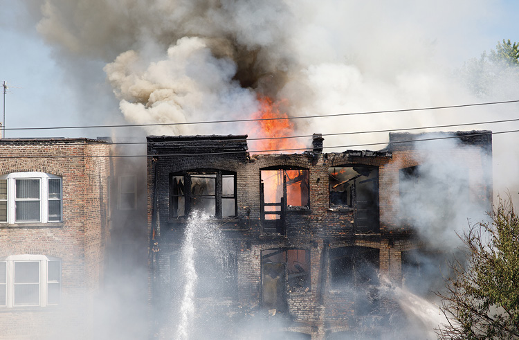 (4) As the fire intensifies, we can see in the center of the photo that a rear porch has collapsed into the rear yard. Members are operating handlines from the rear yard because of the inability to get a master stream in the rear yard. 